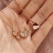 a woman's hand holding four different necklaces