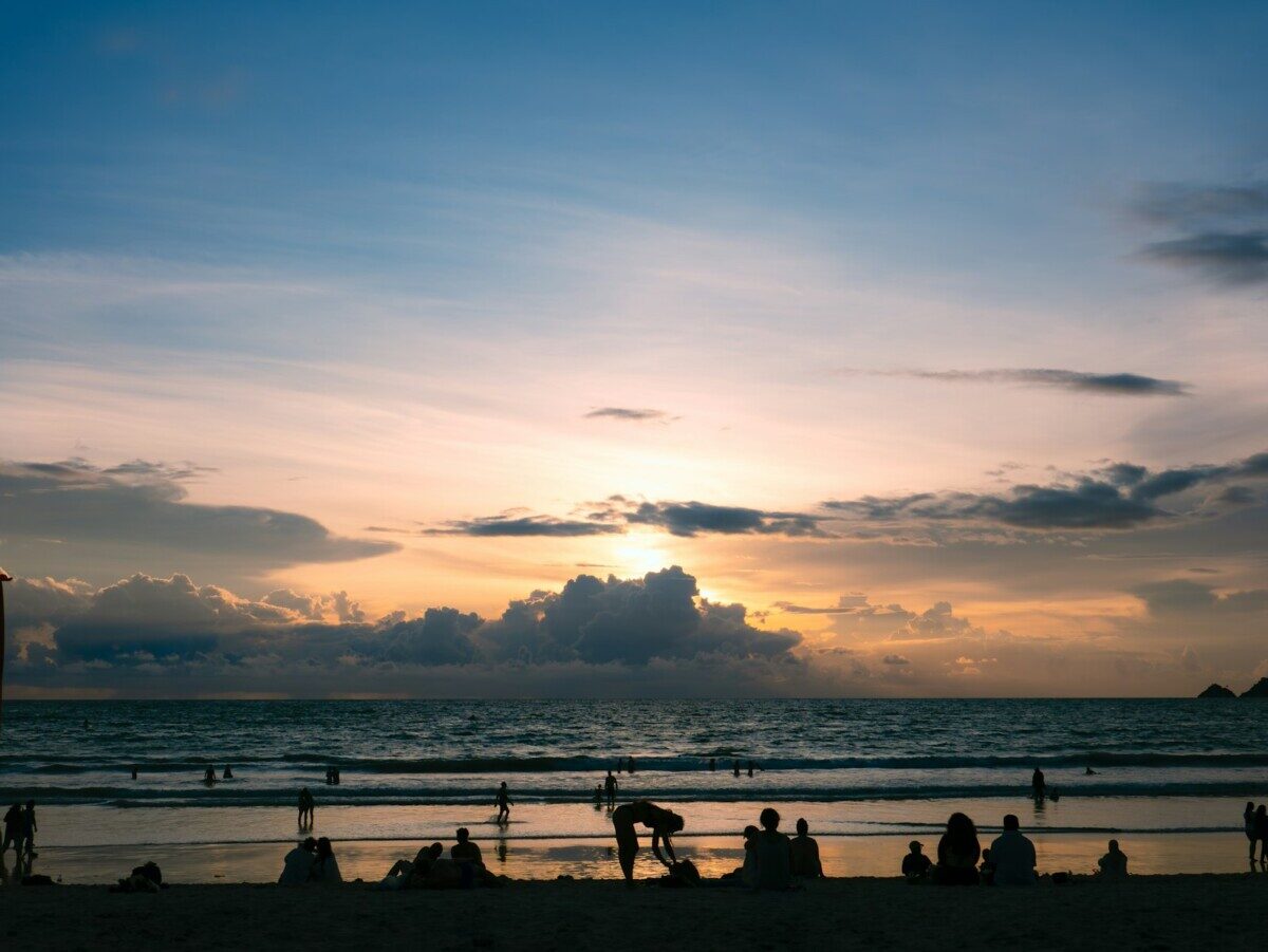 A group of people standing on top of a beach next to the ocean